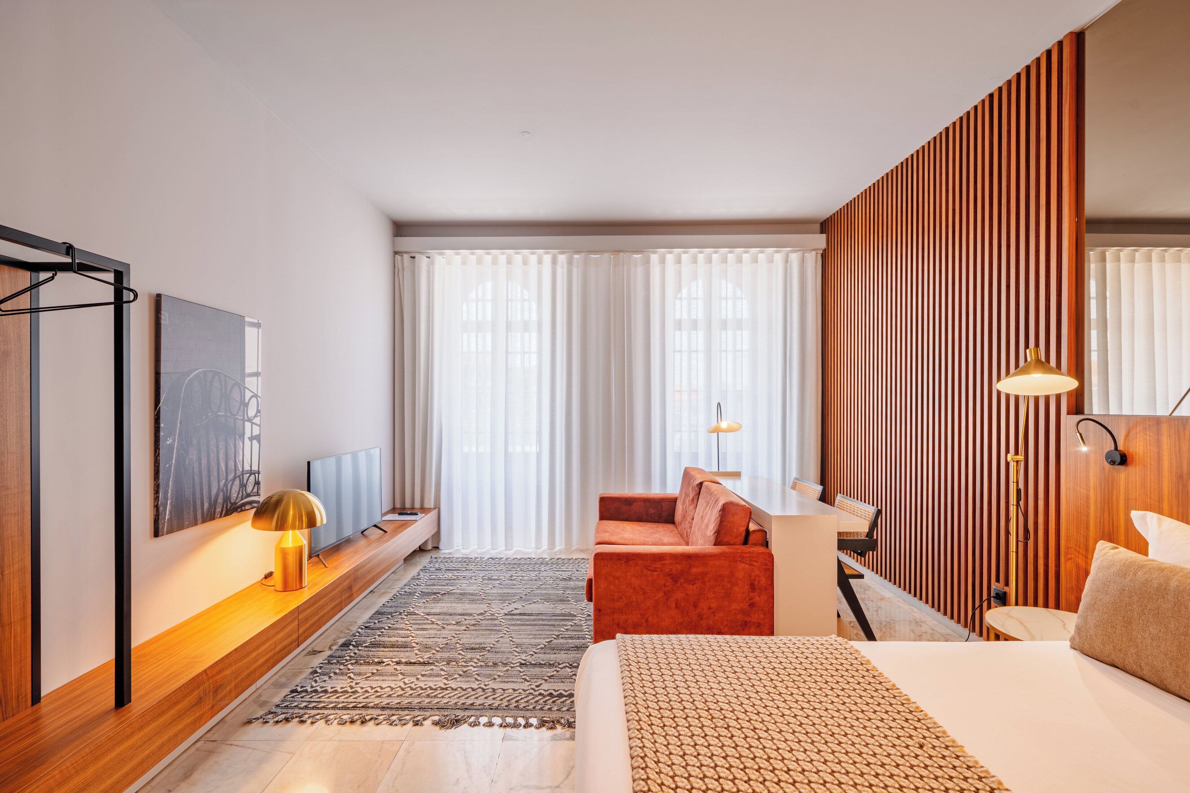 Une chambre d’hôtel moderne équipée d’un lit, d’un canapé, d’un bureau et d’une télévision.