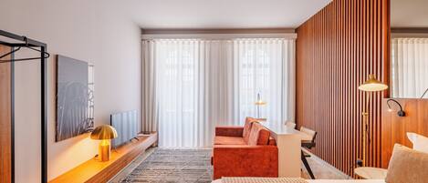 Une chambre d’hôtel moderne équipée d’un lit, d’un canapé, d’un bureau et d’une télévision.