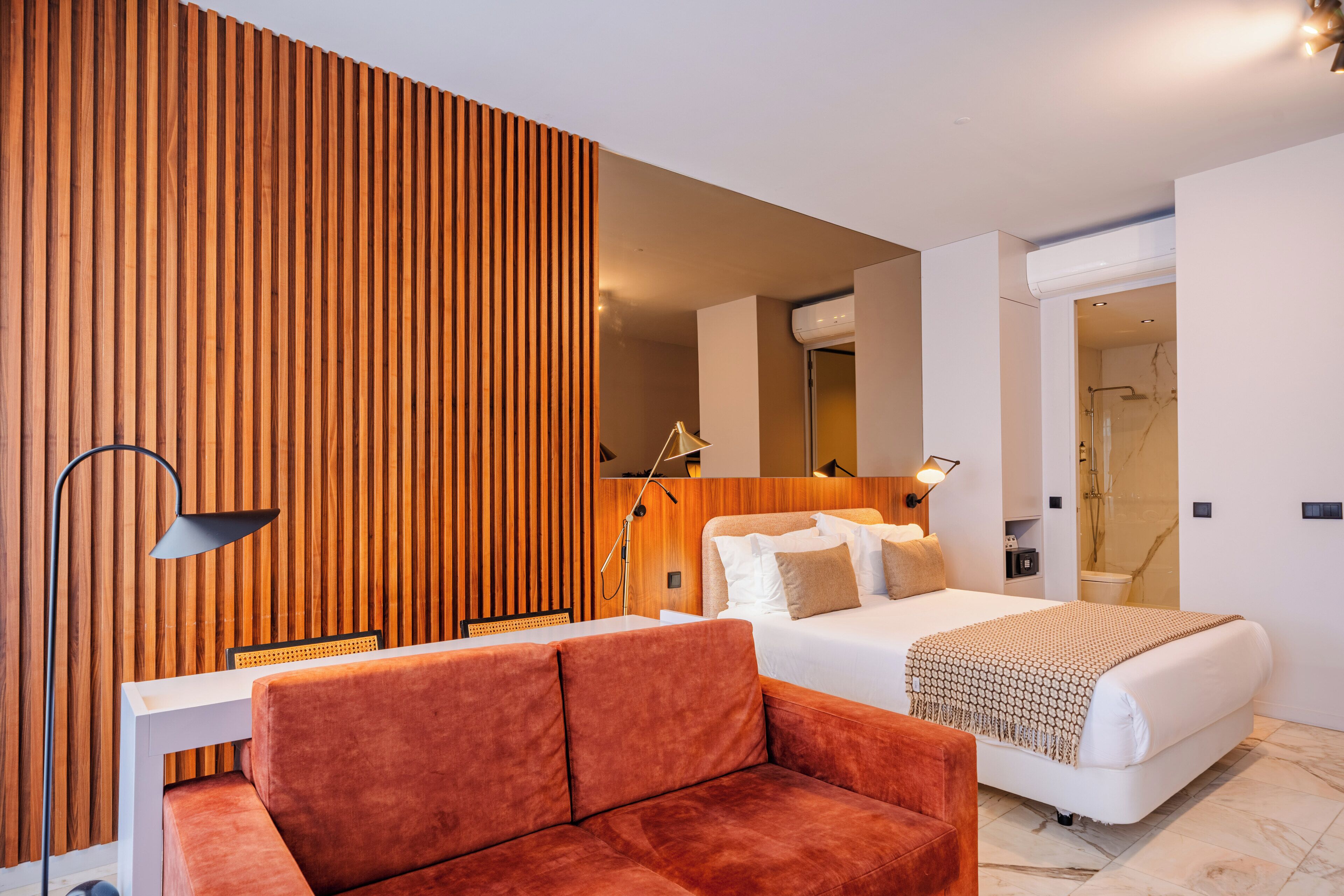 Una habitación de hotel moderna con cama, sofá, escritorio y una pared decorativa de madera.