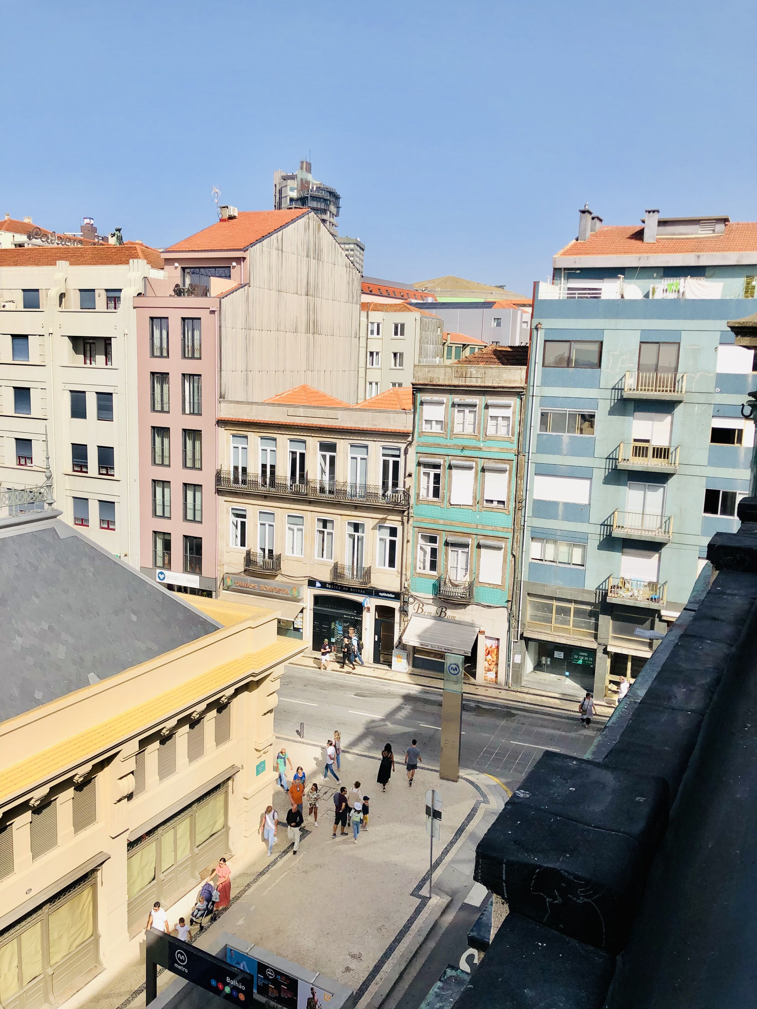 A street view with buildings, pedestrians, and a metro sign.