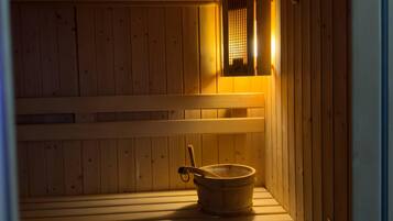 Una sauna con bancos de madera, un balde de madera y un calentador.
