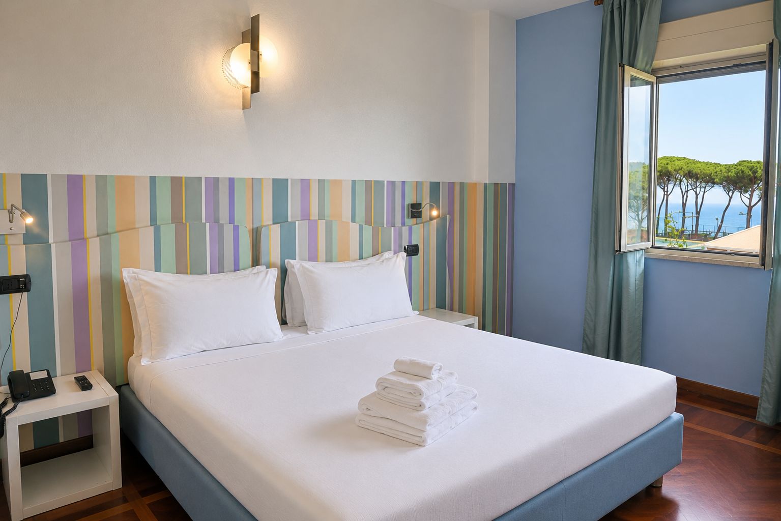 Ein Hotelzimmer mit Bett, Nachttischen und Meerblick.