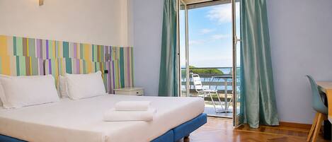 Une chambre d’hôtel avec un lit, un bureau et une vue sur la mer.