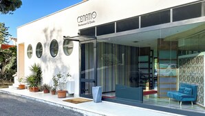 A modern restaurant with a glass facade, outdoor seating, and potted plants. - HA HOTEL (Bracciano)
