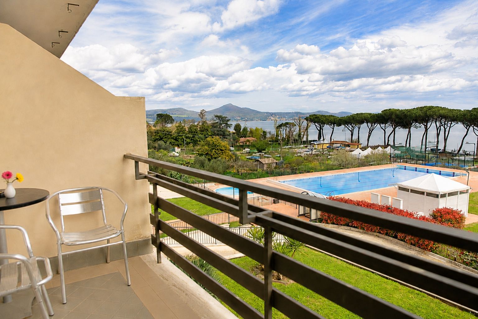Un balcone con vista su una piscina, sedie e un tavolo.