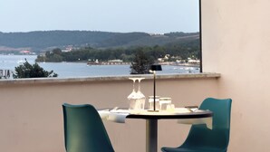 A balcony with a table and chairs, overlooking a body of water and a distant shoreline. - HA HOTEL (Bracciano)
