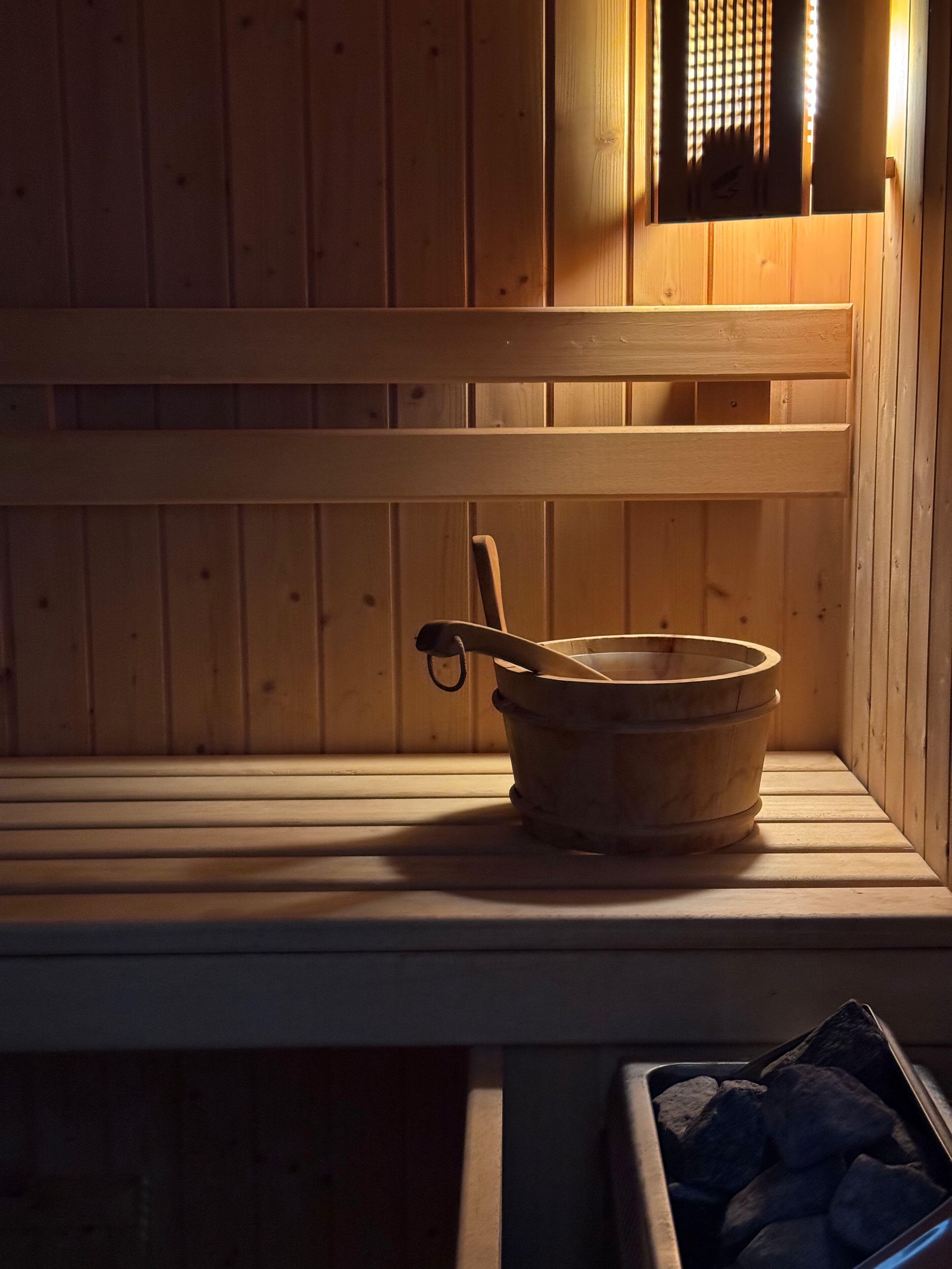 Un banco de sauna de madera con un cubo y una cuchara de madera.