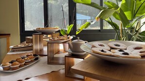 A table with various pastries and a view of a forest through a window. - HA HOTEL (Bracciano)