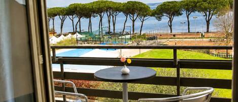 A balcony with a view of a pool and trees.