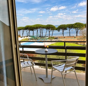 Ein Balkon mit Blick auf ein Schwimmbad und Bäume.