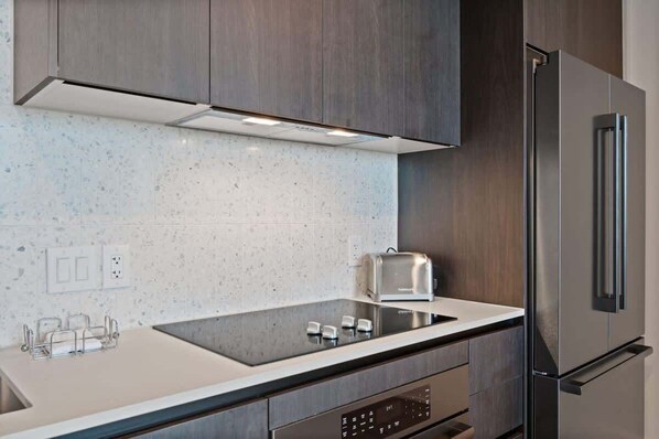 A modern kitchen with a stainless steel refrigerator, a built-in oven, and a toaster on the countertop.