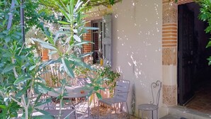 An outdoor patio with a table and chairs, surrounded by greenery and a brick wall. - Comfortable 50 m2 apartment in Marssac sur Tarn, between Gaillac and Albi (Marssac-sur-Tarn)