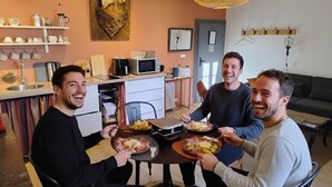 A dining area with a round table, chairs, and a kitchen in the background. - Comfortable 50 m2 apartment in Marssac sur Tarn, between Gaillac and Albi (Marssac-sur-Tarn)