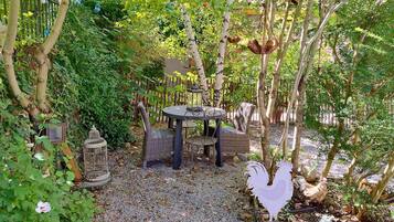 Un espace jardin aménagé avec une table et des chaises, entouré d’arbres et de plantes.