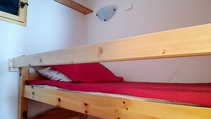 Een stapelbed met houten frame en rode beddengoed.