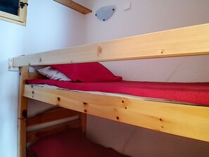 Ein Etagenbett mit Holzbettgestell und roter Bettwäsche.