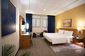 Una habitación de hotel con cama, escritorio, silla y una pequeña mesa.