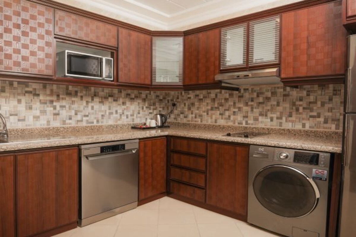 Una cocina moderna con armarios de madera, microondas, lavavajillas y lavadora.