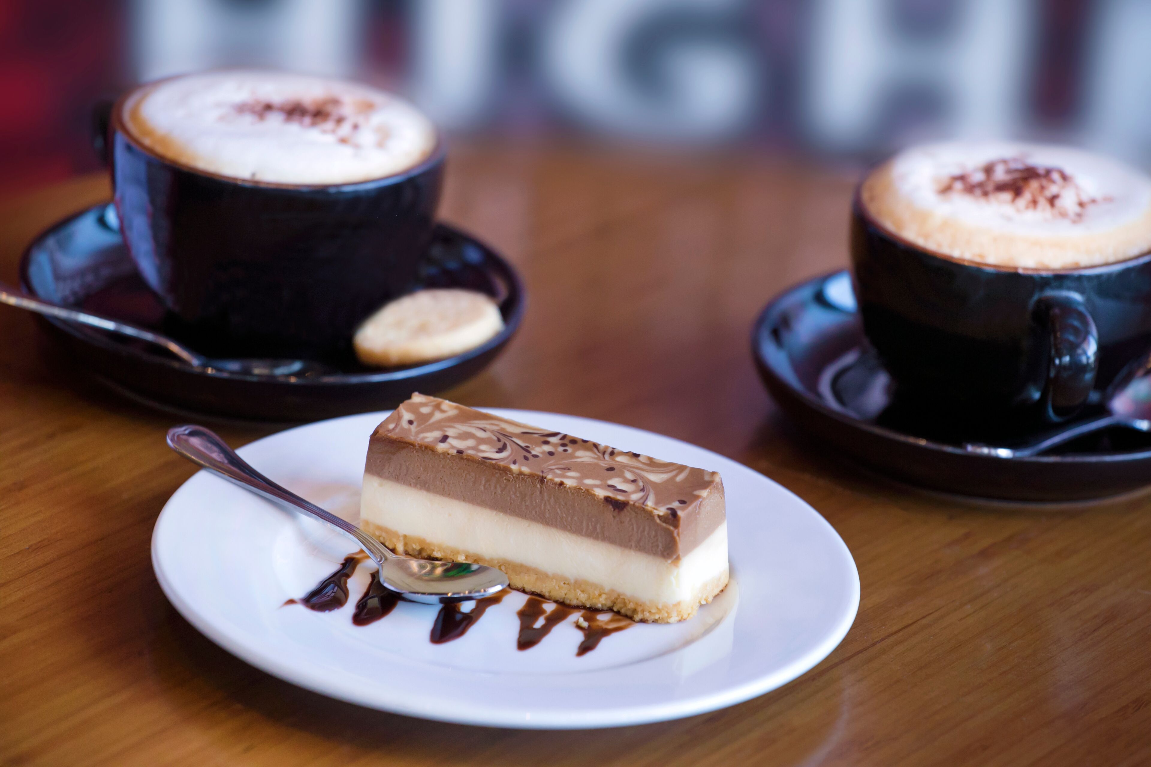 A dessert plate with a slice of cheesecake and two cups of coffee on saucers.