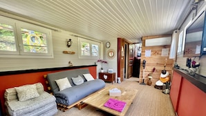 A cozy living area with a sofa, a small table with a tissue box, and a wooden floor.