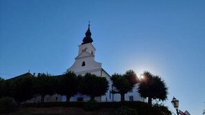 A church with a prominent steeple and a cross on top, surrounded by trees and a lamp post. - Luxury 1-bed Apartment in Varazdinske Toplice (Varazdinske Toplice)