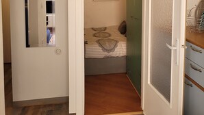 A bedroom with a bed, a mirror, a door, and a green wardrobe.