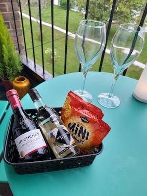 A table with a wine bottle, two glasses, and a snack basket.