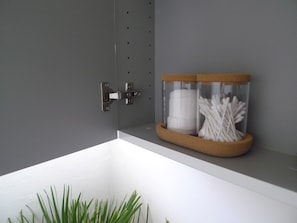 A bathroom with a white sink, a glass jar with cotton swabs, and a metal towel rack.