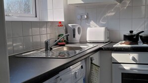 A compact kitchen with a washing machine, a toaster, and a kettle. - NEW! Rustic Loft Escape Bournemouth (5mins to Beach, Uni, Bars, Shops) Park FREE (Bournemouth)