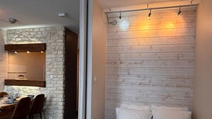 A room with a stone wall, a wooden slat wall, a bed with white pillows, and a dining area with chairs and a table. - Cozy 2-room apartment in Avoriaz for 4 people (Avoriaz)