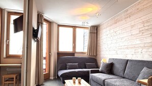 A modern living room with a grey sofa, a wooden coffee table, and a TV mounted on the wall. - Cozy 2-room apartment in Avoriaz for 4 people (Avoriaz)