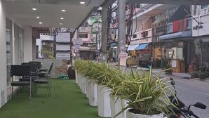 A Lucky Inn Residency with a covered outdoor seating area, artificial grass, and potted plants. - Lucky Inn Residency (Pattaya)