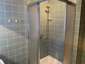 Een douche met een glazen deur, een handdouche en een wandmengkraan.