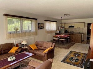 A living room with a sofa, a coffee table, and a dining area with a table and chairs.