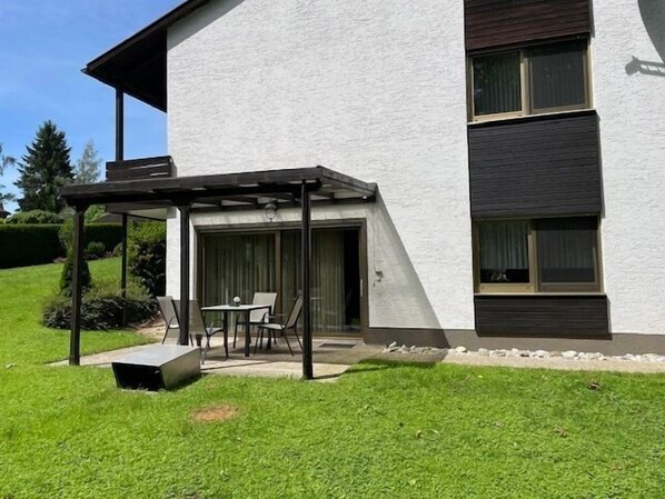 Un bâtiment moderne doté d’un espace extérieur couvert avec des sièges, d’une porte et d’une fenêtre.