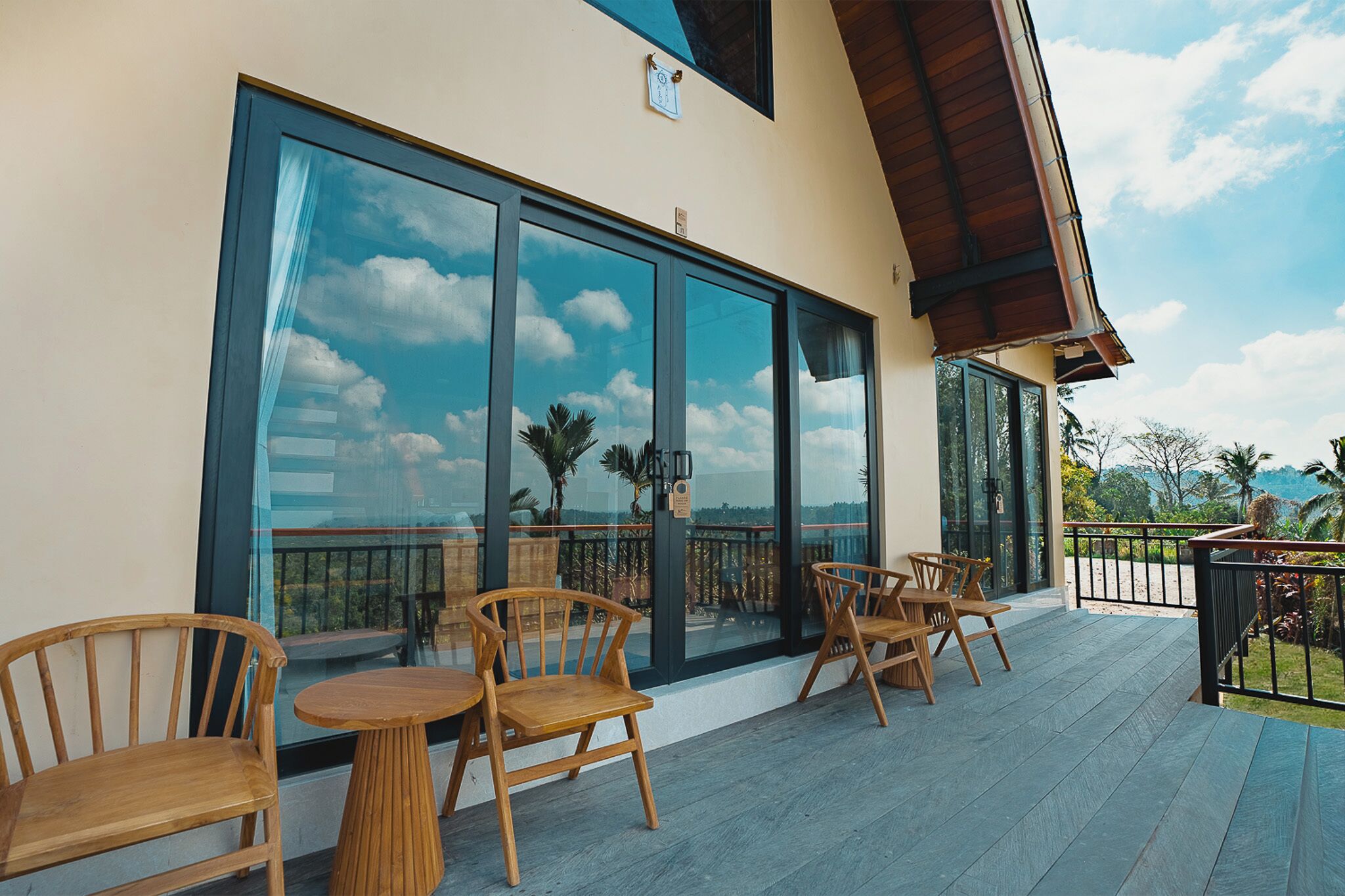 A terrace with wooden furniture and large windows overlooking a landscape.