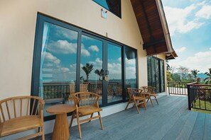 Une terrasse dotée de mobilier en bois et de grandes fenêtres donnant sur un paysage.
