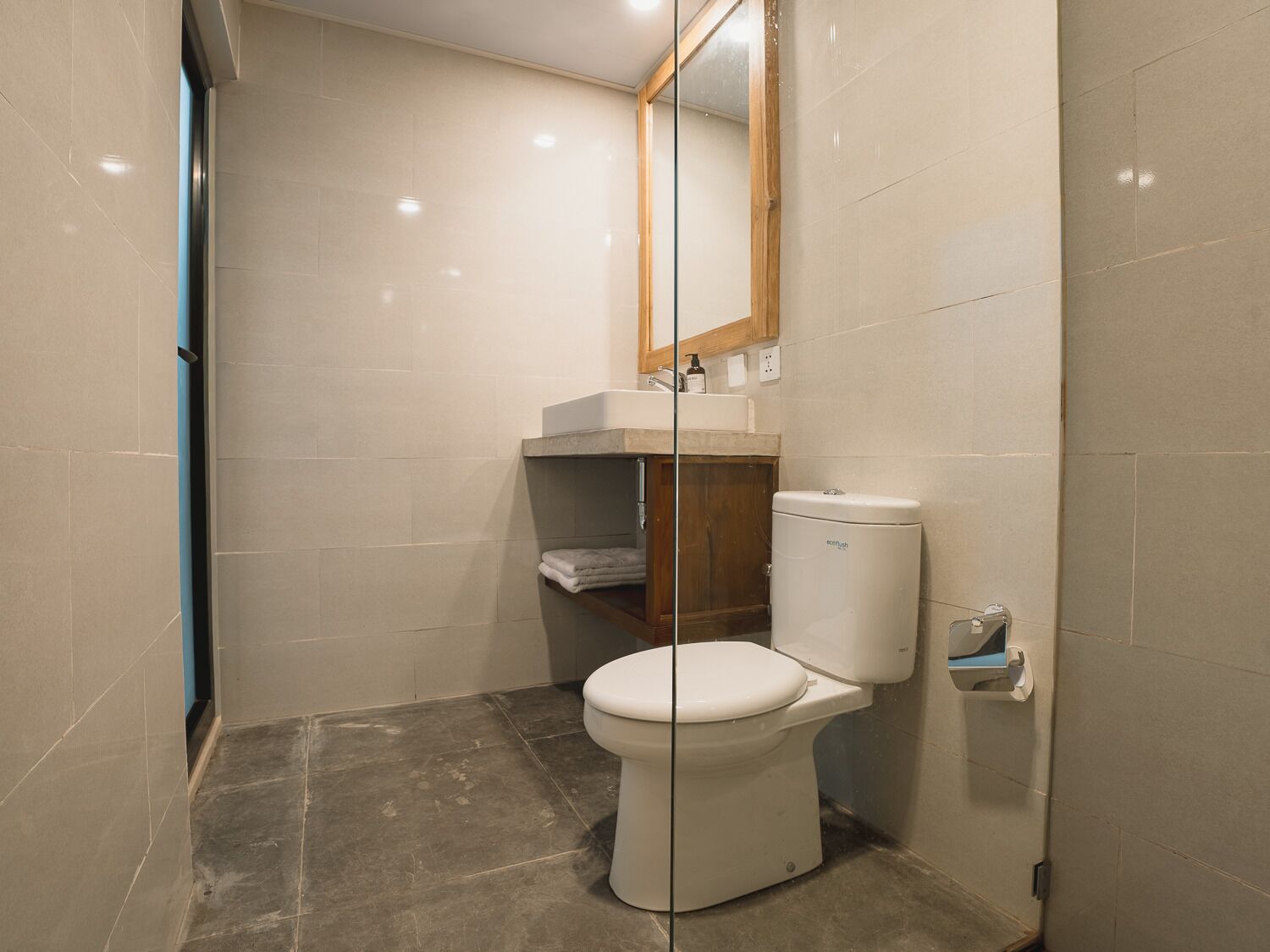 A small, modern bathroom with a toilet, a sink, and a mirror.