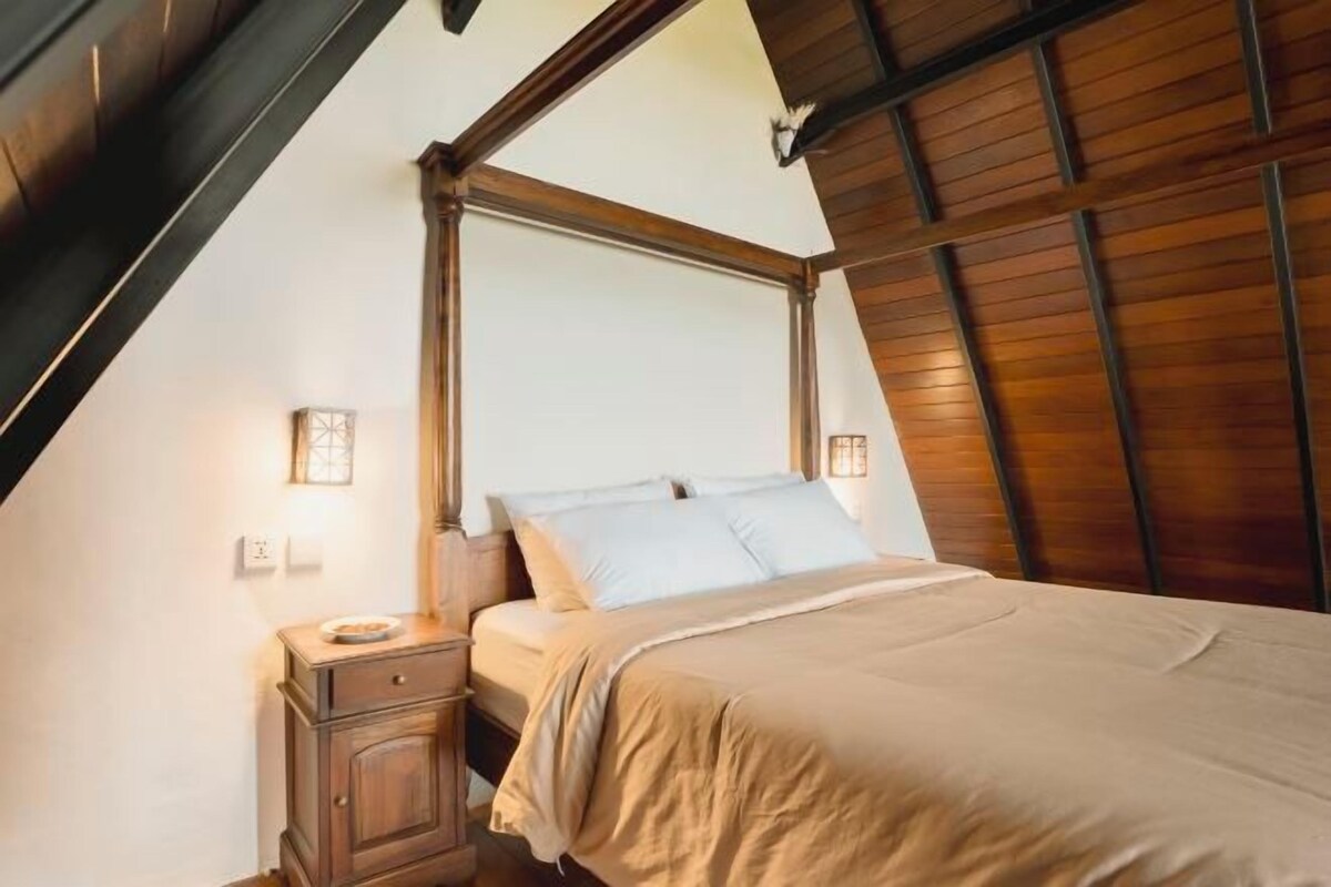 Une chambre à coucher avec une tête de lit en bois, un lit recouvert d’une couvre-lit beige et des lampes de chevet.