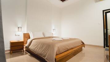 Un dormitorio con una cama de madera, una mesita de noche, una lámpara de pared y un ventilador de techo.