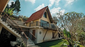 Ein zweigeschossiges Haus mit rotem Ziegeldach, einem Balkon und einer Treppe, die zum Obergeschoss führt.