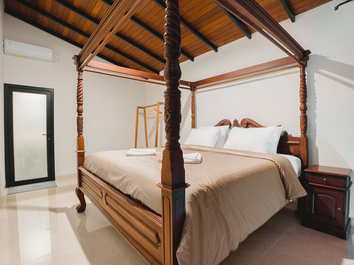 A four-poster bed with a wooden frame, a bedside table, and a wardrobe.