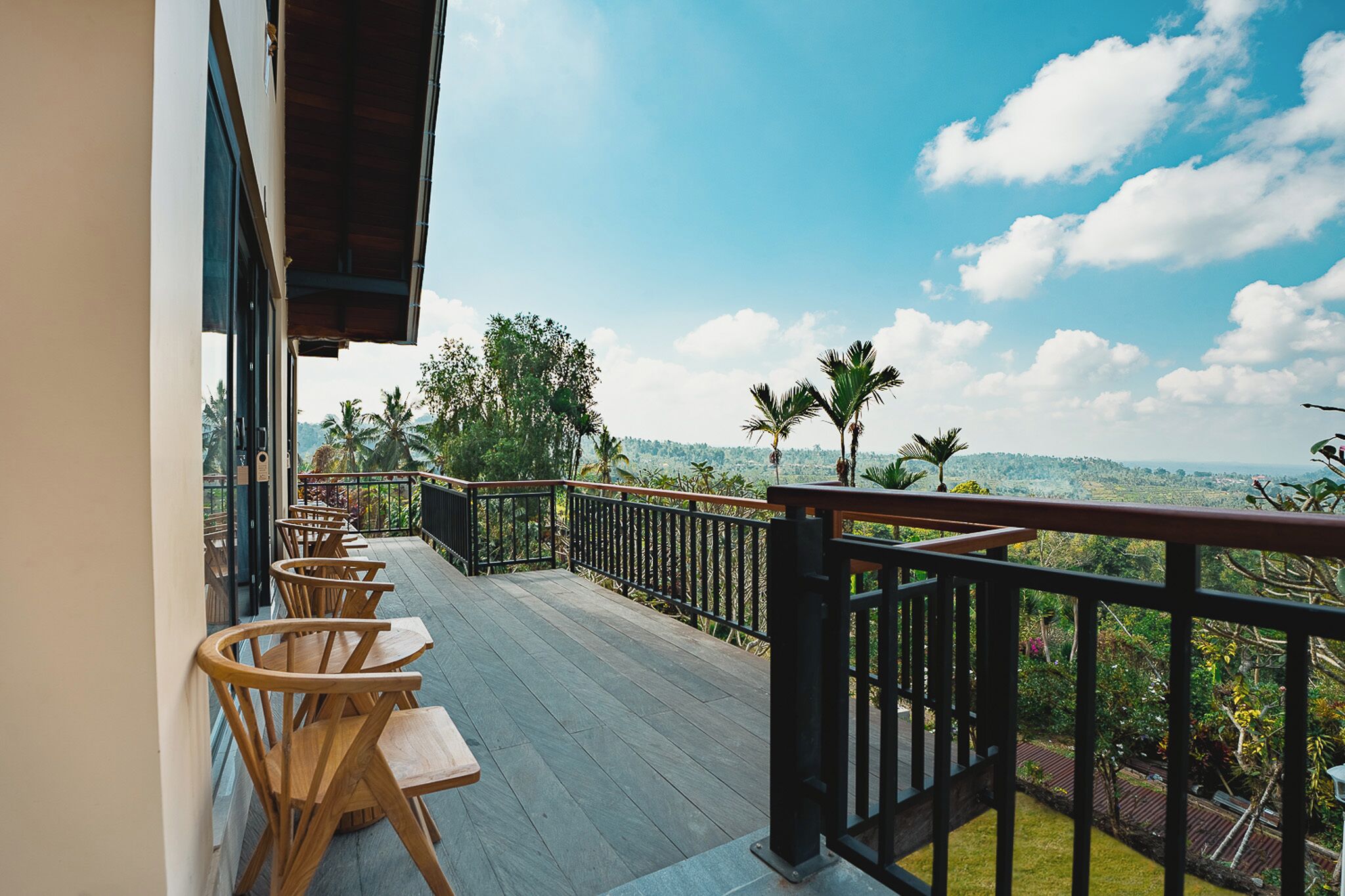 Una terraza de madera con asientos al aire libre, barandilla y vistas a un paisaje montañoso.