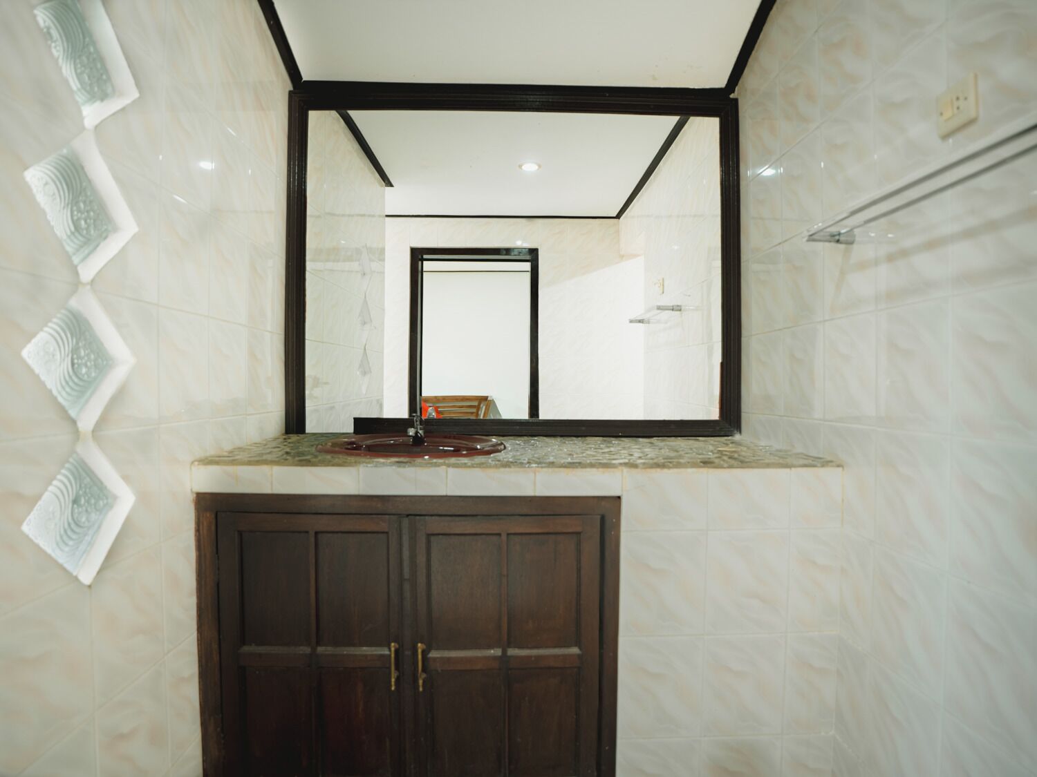 A bathroom with a marble vanity, a large mirror, and a wooden cabinet.