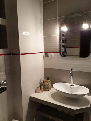 A bathroom with a white sink, a mirror, and a toothbrush holder. - Charming 2-bed Apartment in Krakow (Kraków)