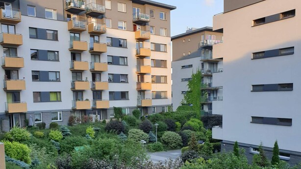 Kerrostalo, jossa on useita parvekkeita ja hyvin hoidettu puutarha-alue.