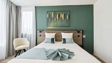 A hotel room with a large bed, two pillows, a chair, and a wall art piece.