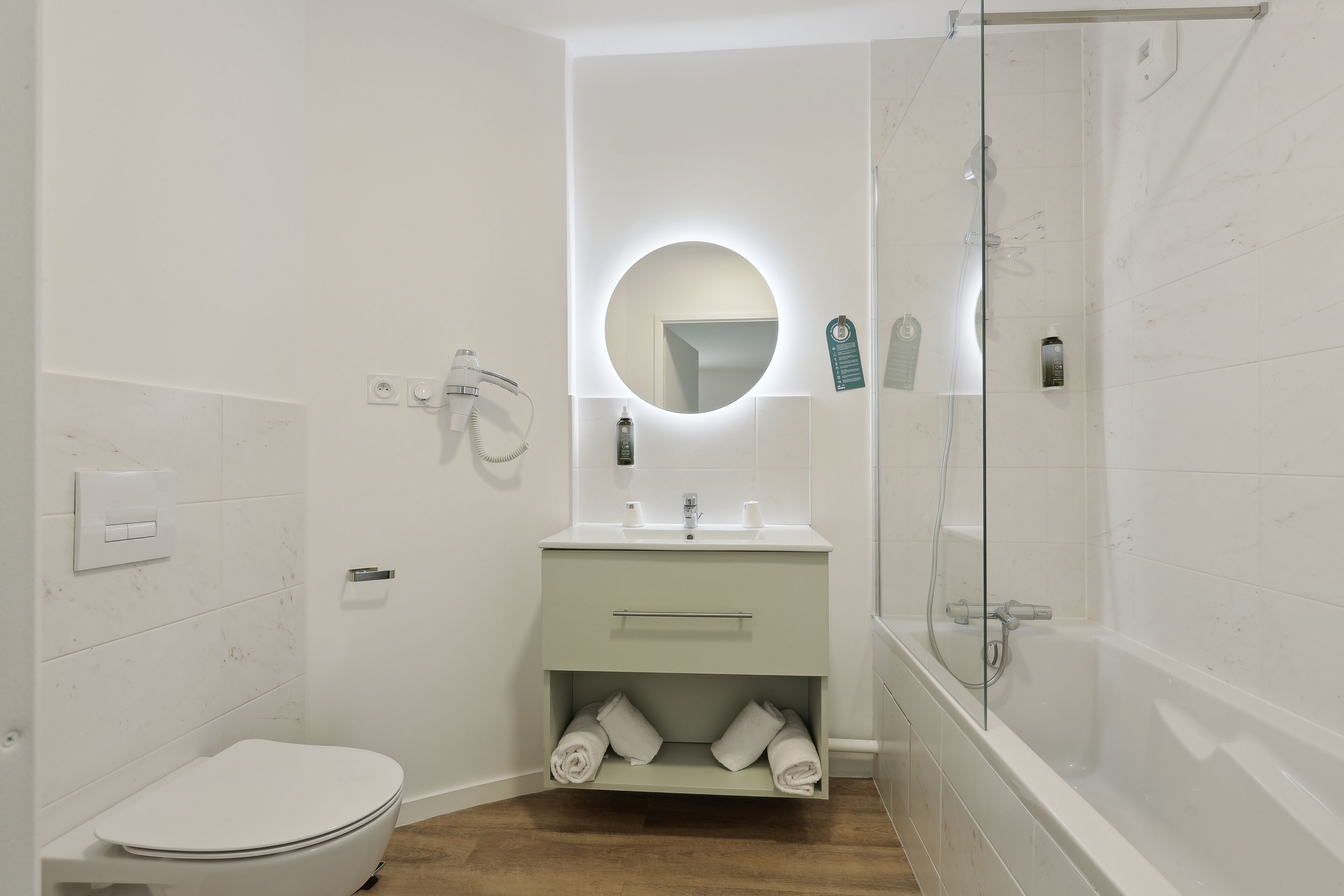 Et moderne badeværelse med toilet, håndvask med spejl, brusebad og et bruseområde med glasvægge.