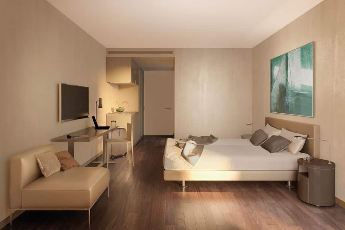 Een moderne hotelkamer met een bed, bureau, stoel en televisie.