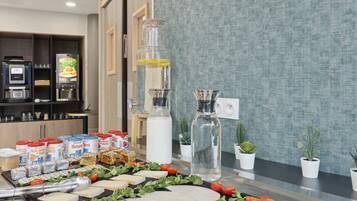 A buffet setup with various food items, a coffee machine, and potted plants.
